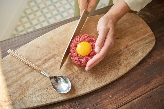 Crop woman preparing delicious steak tartare