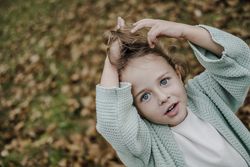 Smiling girl between meadow with dry leaves