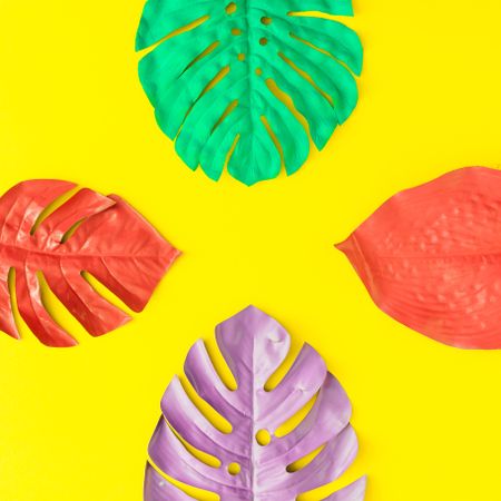 Painted tropical and palm leaves in vibrant bold colors on yellow background