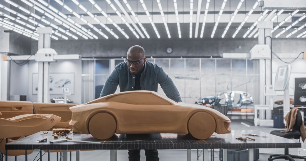 Black Creative Automotive Designer Working on a Prototype Car Out of Polymer Modeling Clay.