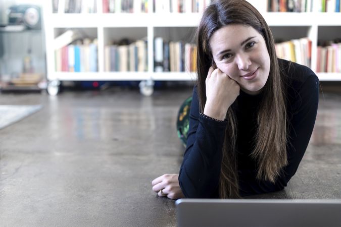 Young entrepreneurial woman in front of laptop on floor with copy space