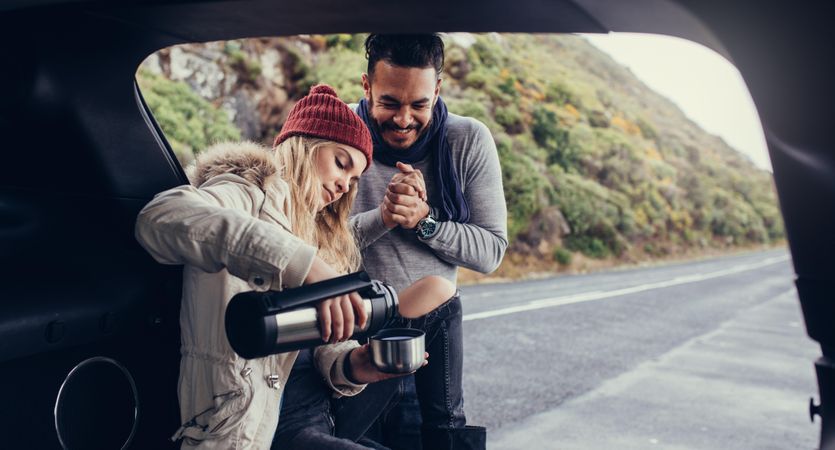 Young woman serving boyfriend coffee from thermos