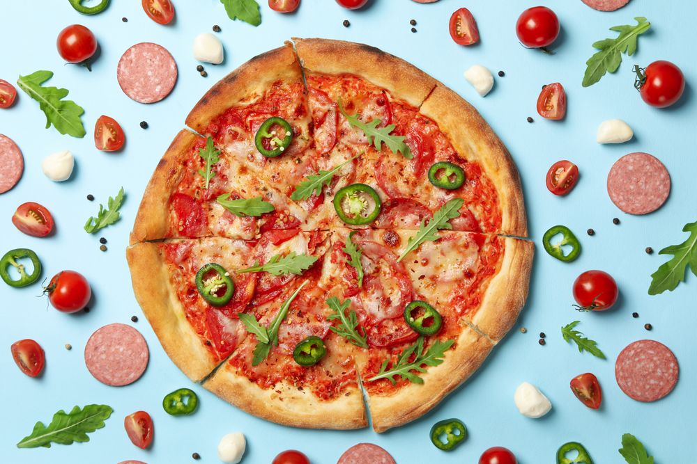 Tasty pizza and ingredients on blue background