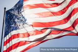 Backlit American Flag Waving In Wind Against a Deep Blue Sky 5r9xY3