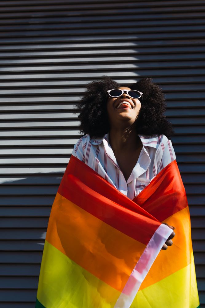 Happy Black woman posing happily with the LGBT flag