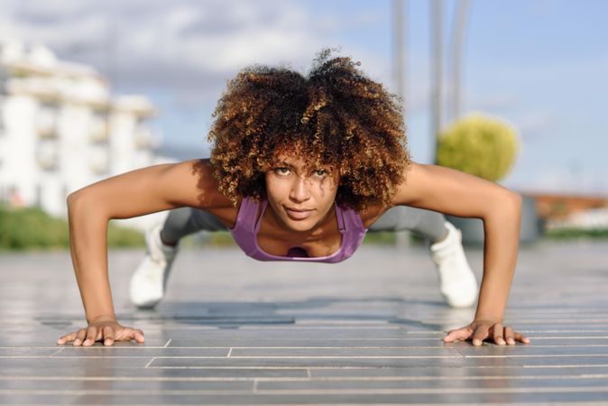 Healthy female with afro hairstyle doing planks outside