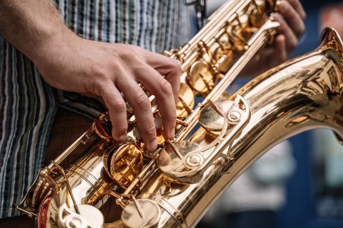 Crop view of male saxophonist playing sax in the street