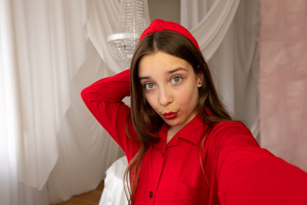 Teen girl posing for playful selfie in bright interior.