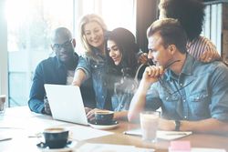 Multi-ethnic group of friends all focused on a laptop
