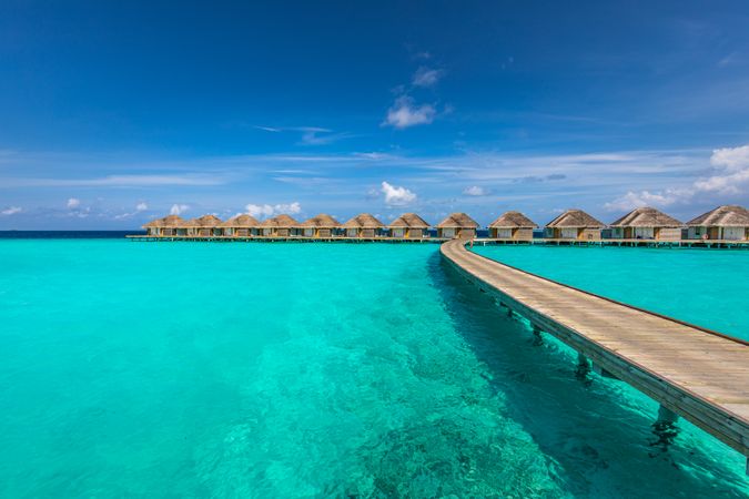 Walkway over clear blue water leading to holiday villas in the Indian Ocean
