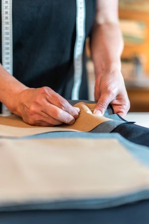 Fashion designer putting pins into pattern and fabric. Vertical shot