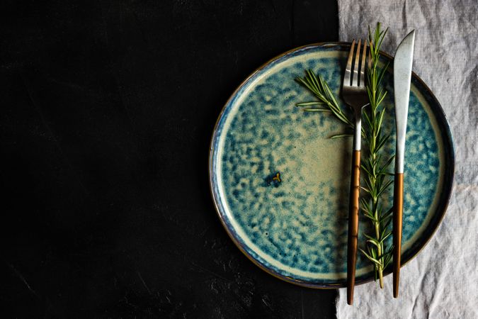 Christmas table setting with blue plate with rosemary herb