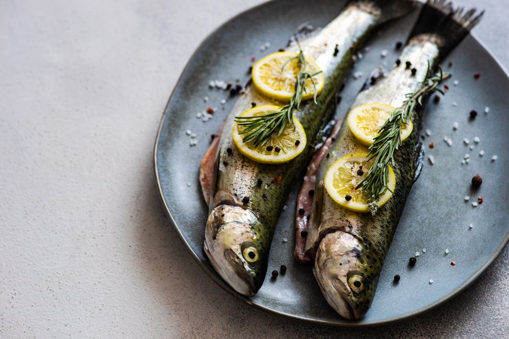 Two trout fish ready for cooking with lemon & herbs