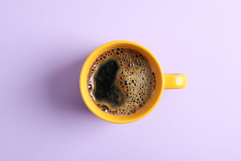 Cup of coffee on color background, space for text