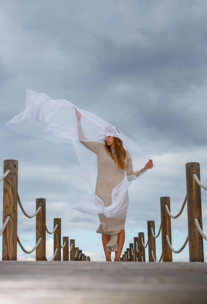 Woman with textile posing in air on footbridge