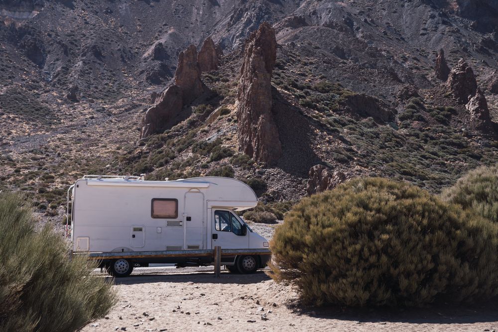 Camper on road against rocky mountains