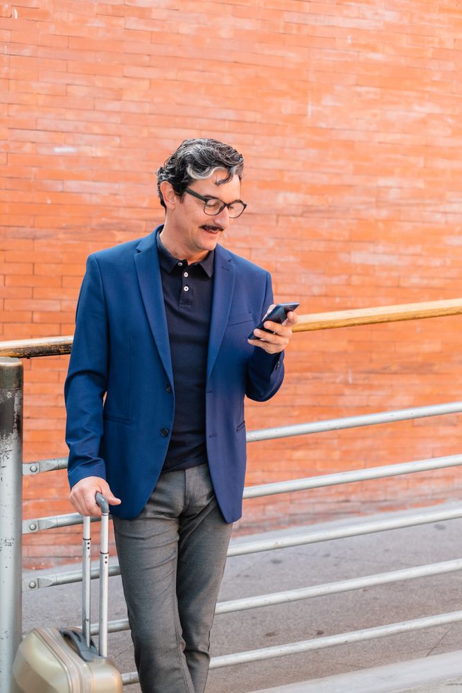 man standing with baggage and talking on smartphone