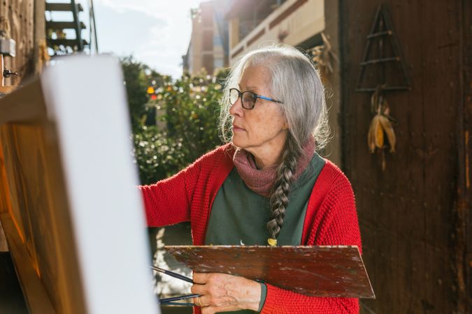 Mature woman painting on canvas in garden