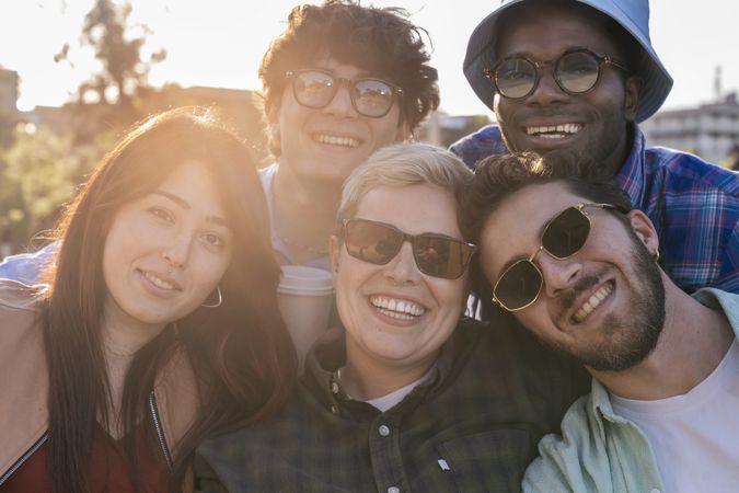 Group of diverse young friends smiling together at sunset showing authentic joyful connection