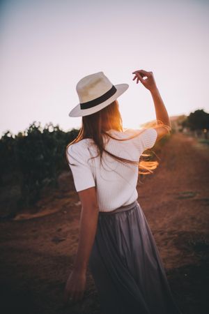 Back of young woman looking off in the distance at sunset