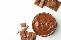 Bowl with chocolate and chocolate pieces on neutral background