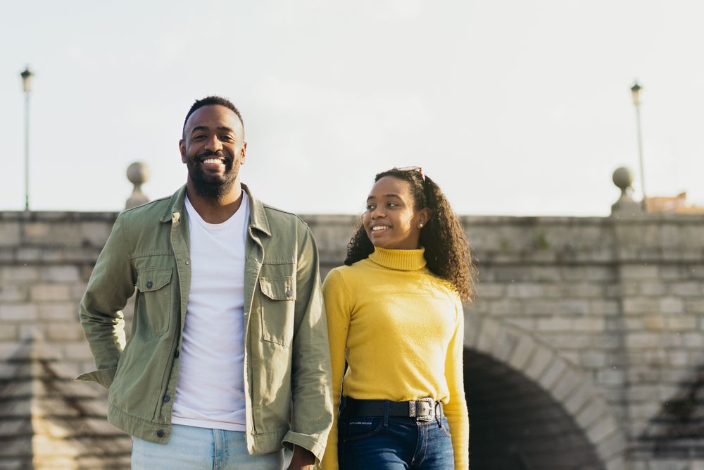 smiling Black couple portrait in front of a bridge