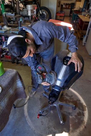 Man polishing motorbike tank in workshop