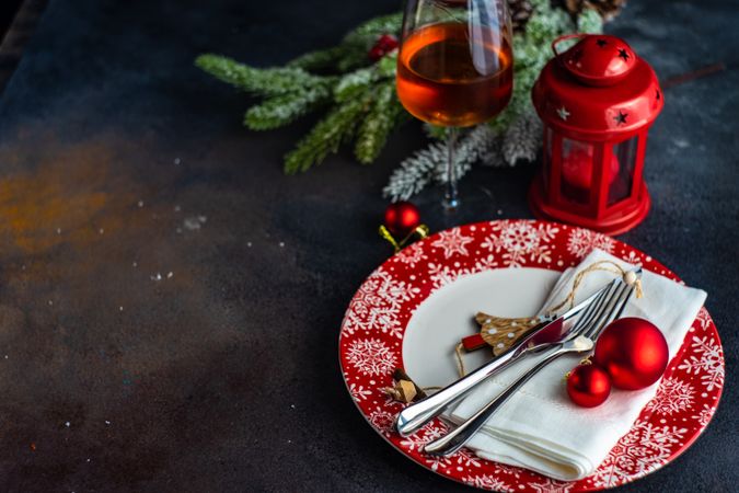 Holiday table setting on red plates with lantern and glass of wine and copy space
