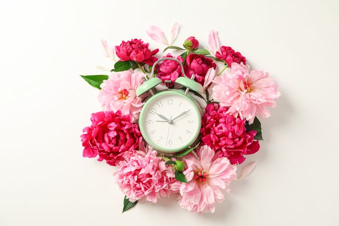 Flat lay composition with beautiful peonies and alarm clock on bright background, space for text