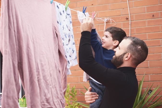 Father and son hanging clothes on rope