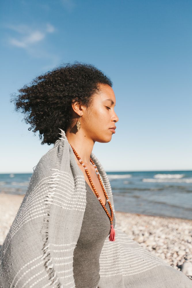 Sportive woman sitting on sandy beach in asana