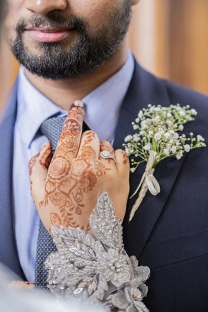 Bride's henna tattooed hand on the shoulder of groom