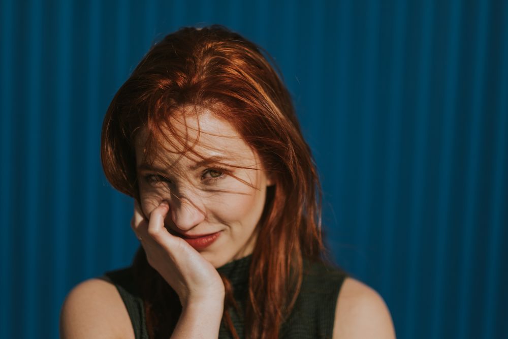 Smiling woman squinting in sun and enjoying weather