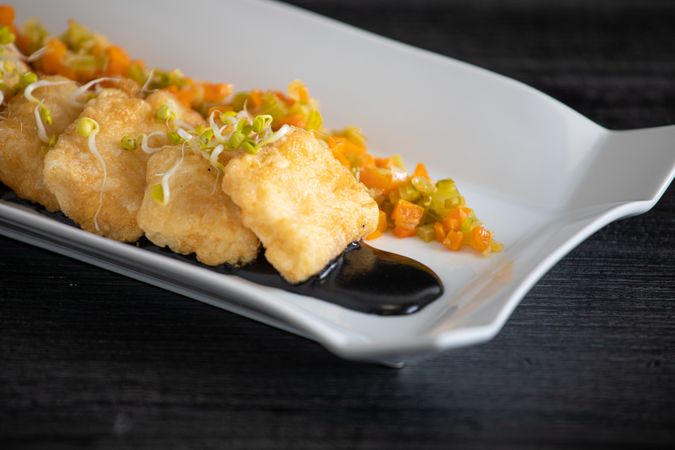 Hake breaded with matignon in white rectangular plate