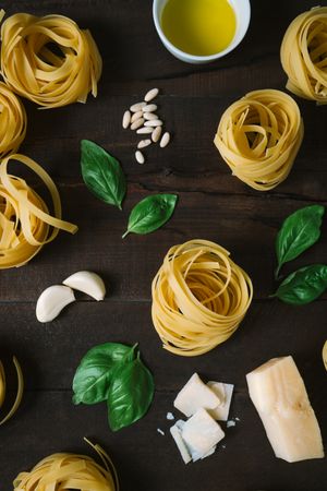 Rows of raw tagliatelle pasta with basil leaves on table