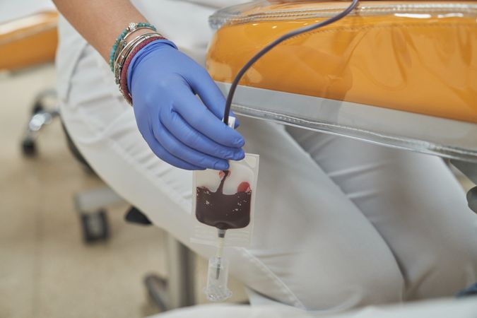 Crop doctor performing blood donation procedure in clinic