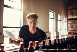 Young male inspector working in alcohol manufacturing factory checking beer bottles 43eAR0