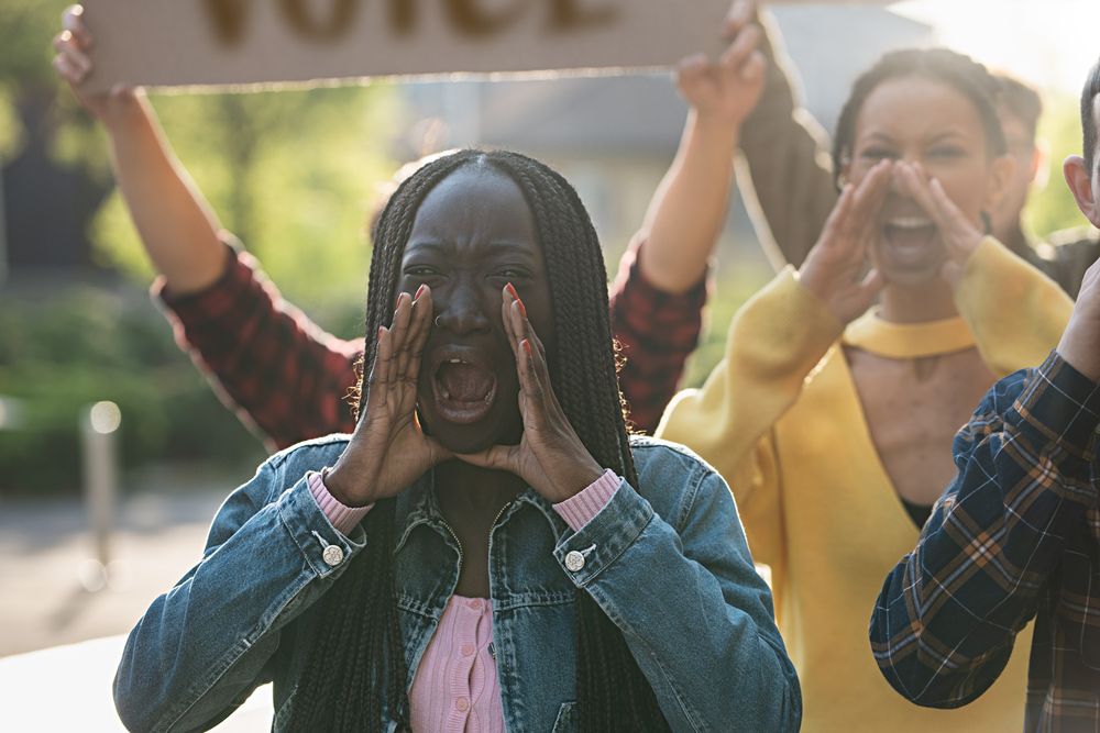 Black woman with dreadlocks shouting during a protest in a city street