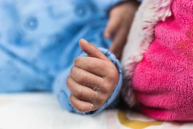 Anonymous newborn baby lying on big soft toy
