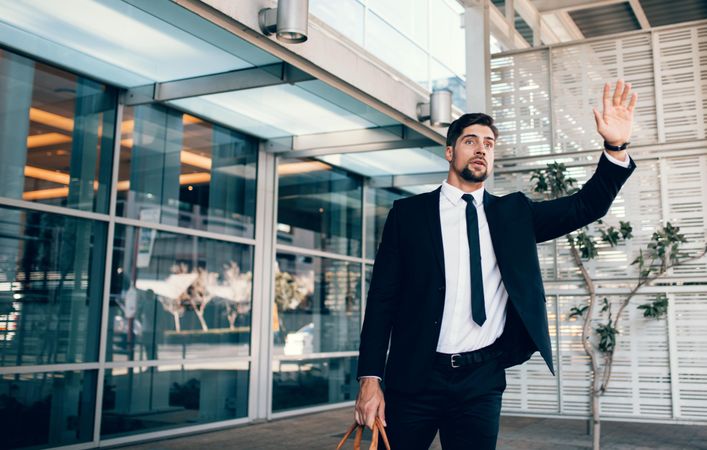 Young white business executive calling cab at the airport terminal