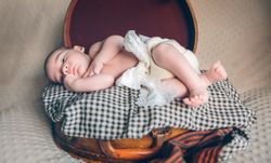 Newborn baby resting lying above of travel suitcase