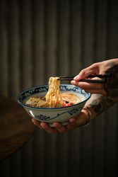 Crop person eating ramen noodles from bowl