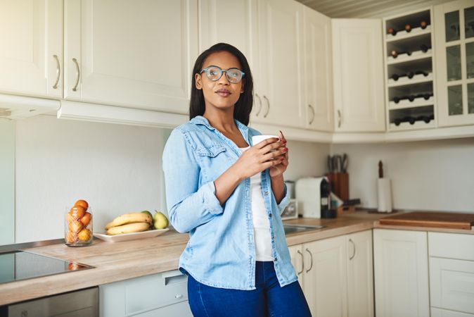 Contemplative woman in kitchen with cup of coffee