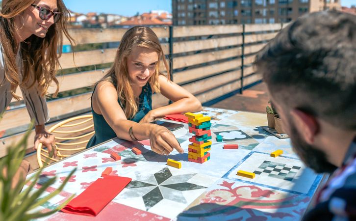 Woman looking game piece next to colleagues on terrace