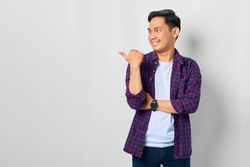 Asian male in grey studio with thumb to the side