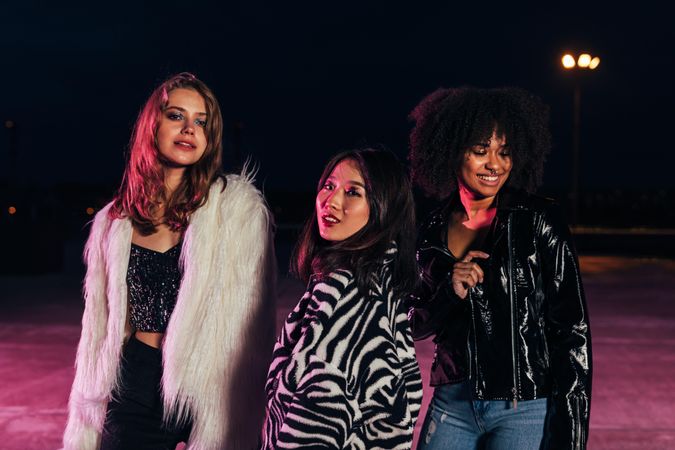 Multi-ethnic group of women in stylish clothes posing at night