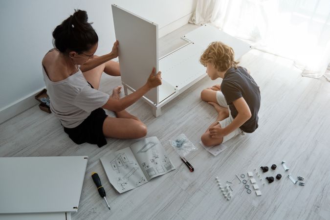 Mother and son assemble furniture according to instructions