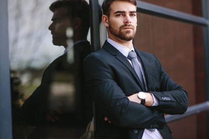 Portrait of confident businessman standing by office building