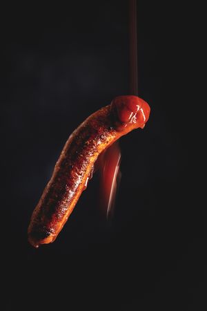 ketchup falling on grilled sausage