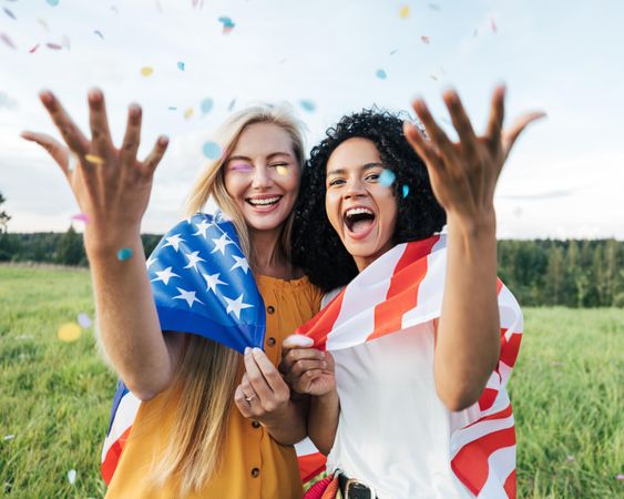 Two women with confetti wrapped in American flag